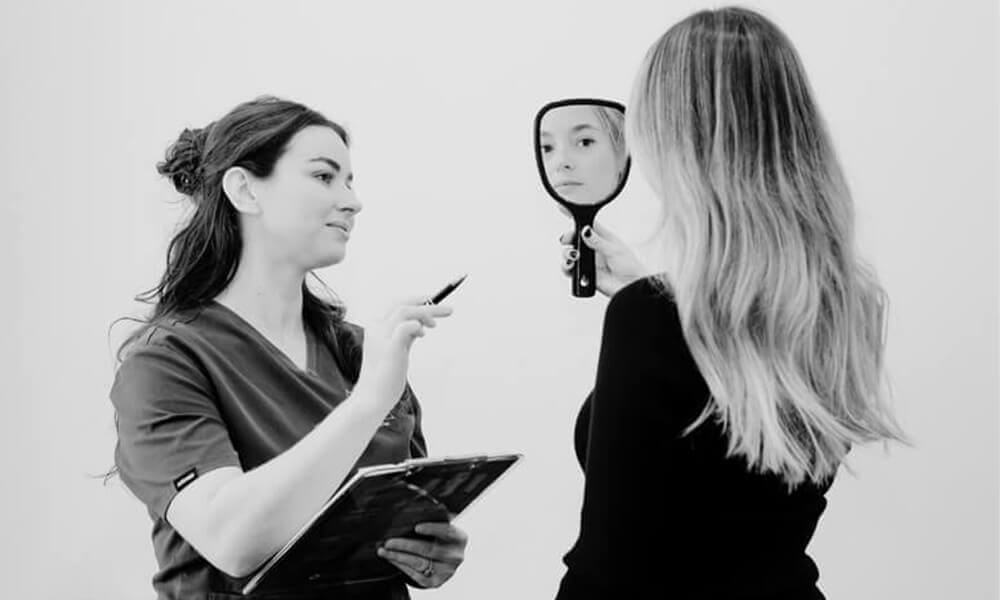 Woman looking in the mirror following a laser facial in Noosa