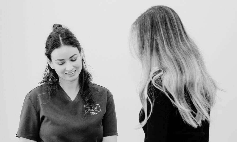 Young woman speaking with a nurse inside PSQ's Gold Coast plastic surgery clinic about lip filler treatments